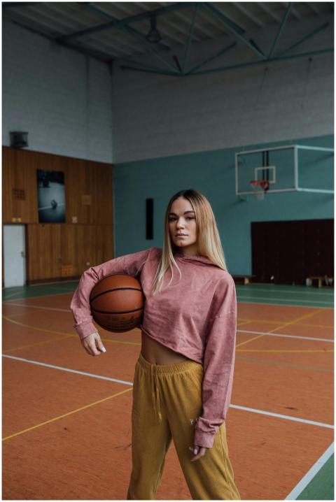 Confident woman holding a basketball on an indoor