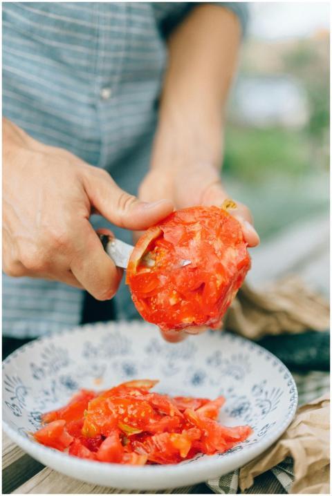 Close-up of a man slicing juicy red tomatoes over