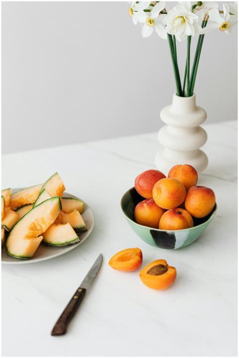From above bowl of fresh ripe apricots and sliced