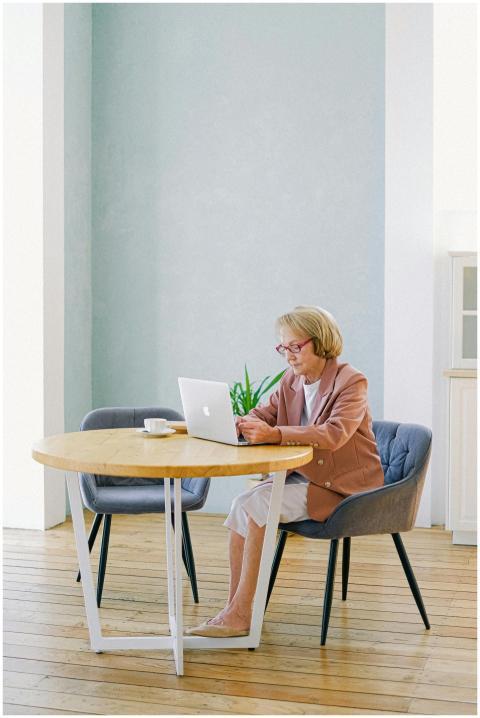 Elderly woman with glasses using a laptop at a bri