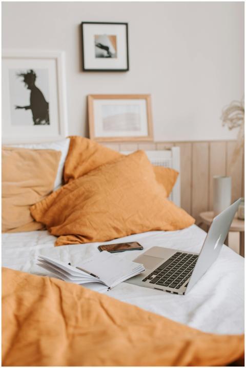 Comfortable disheveled empty bed with orange pillo