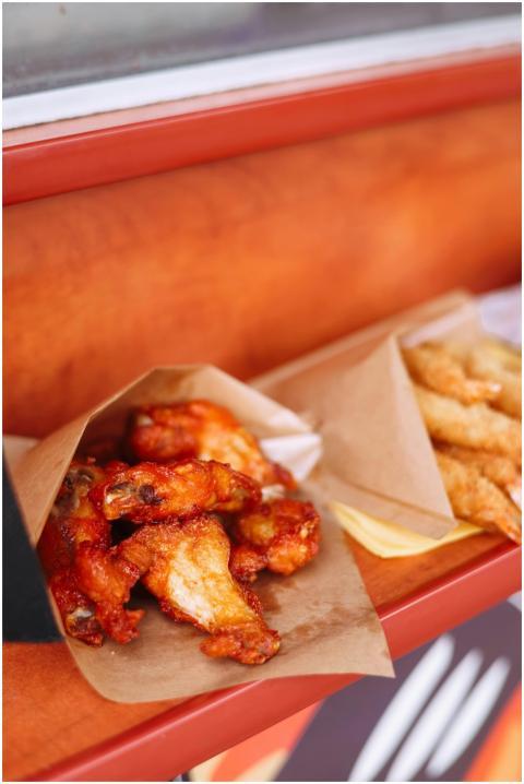 Crispy hot chicken wings served with fries in pape