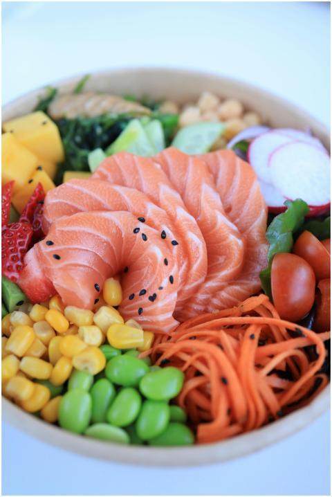 A colorful poke bowl with salmon, vegetables, and