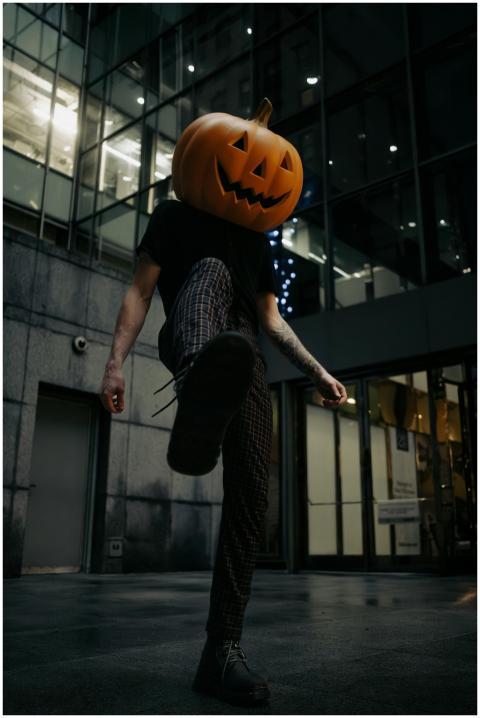 A man with a carved pumpkin head strolls through a