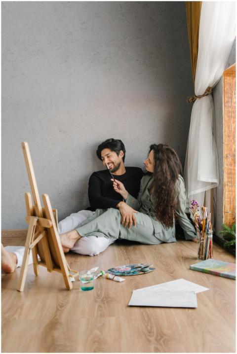 A couple smiles while painting together at home, c