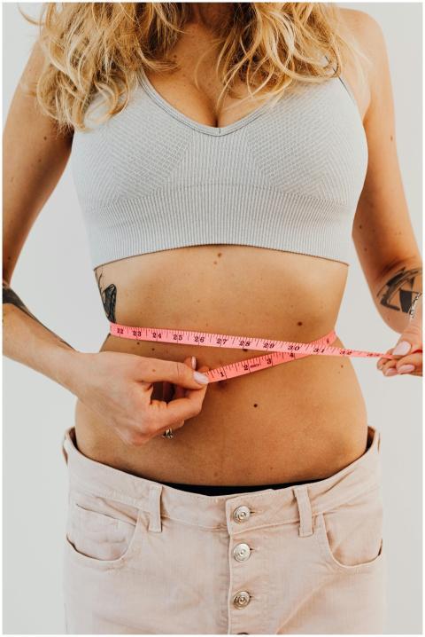 Close-up of a woman measuring her waistline with a
