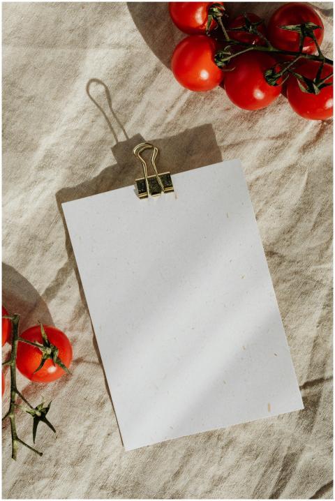 A blank sheet with tomatoes on a textured linen ba