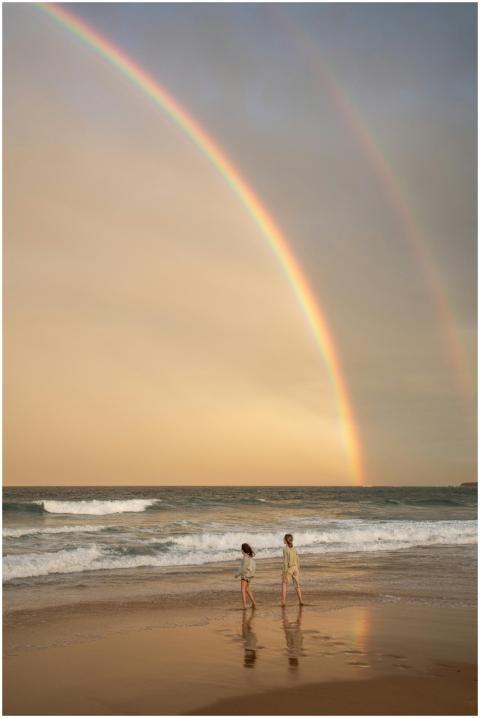 Two children walking along a beach under a vibrant