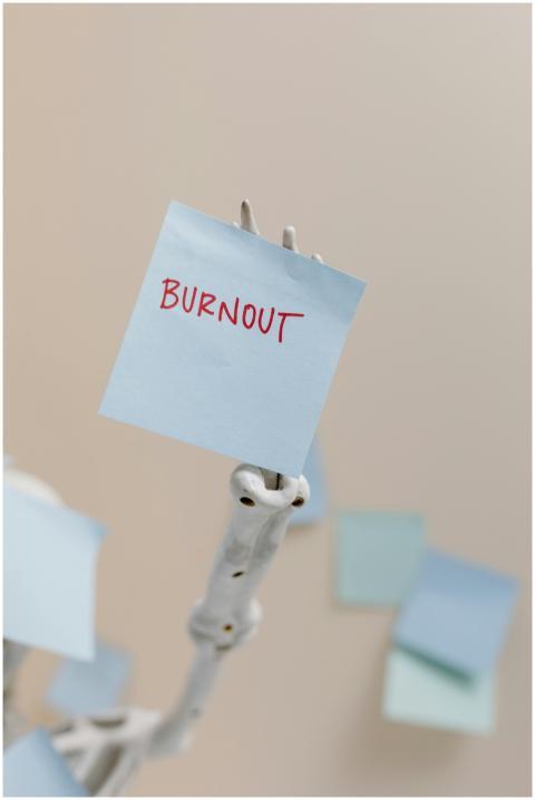A skeleton holding a sticky note reading 'Burnout'