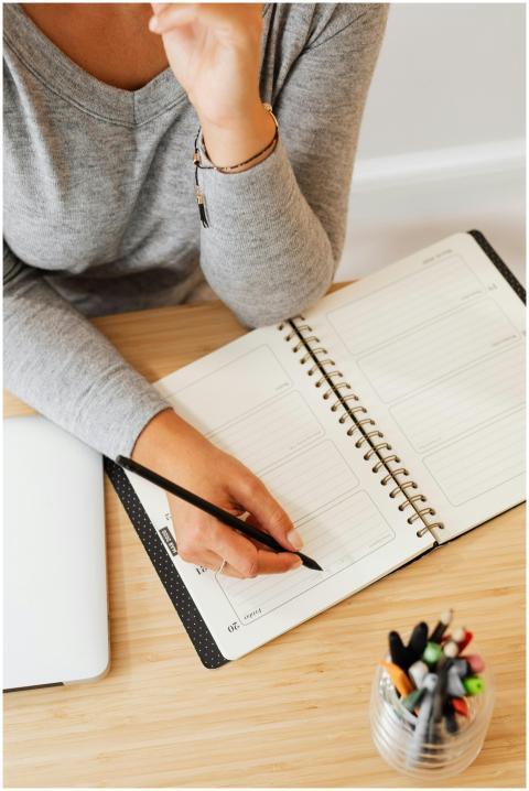 Overhead view of a woman writing in a planner, ide