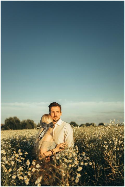 A couple embraces in a lush chamomile field under