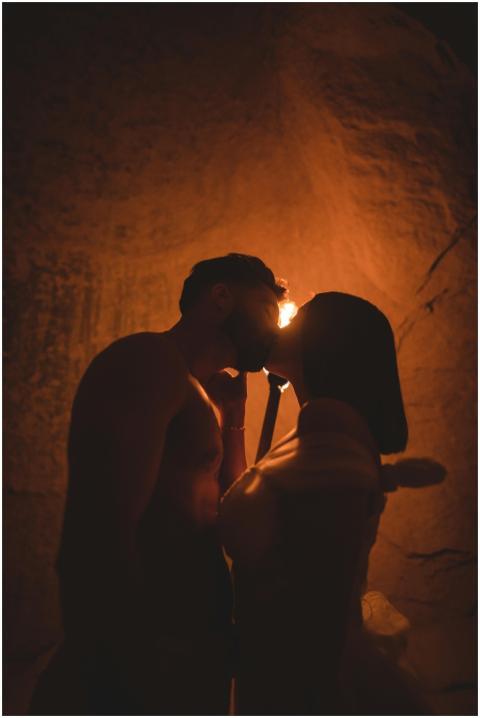 Silhouetted couple sharing a kiss in a dimly lit c