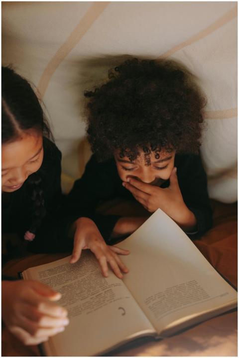 Two children enjoy reading a book together in a di