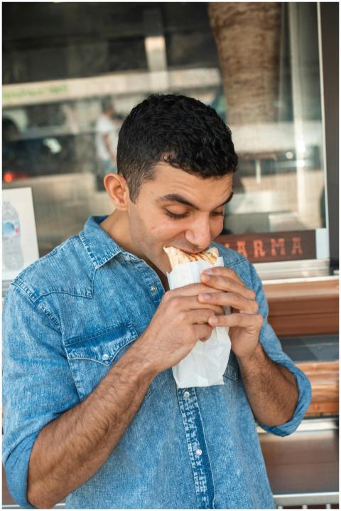 Man in denim shirt enjoying a tasty shawarma outdo