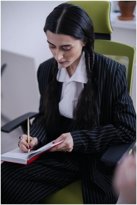 A professional woman in a blazer writes notes in a