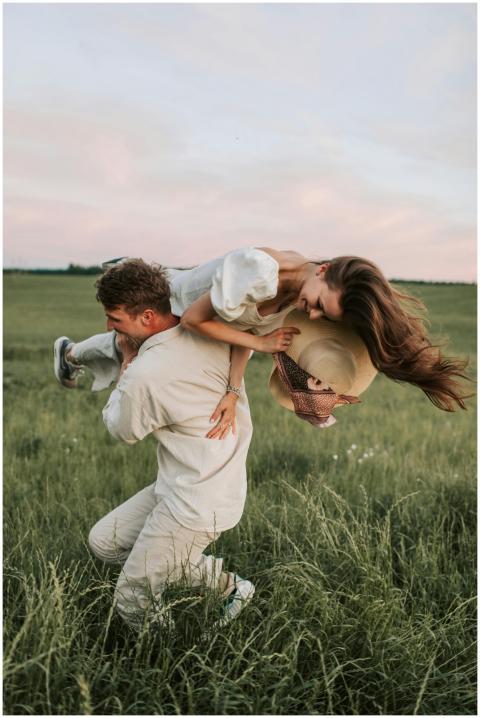 A couple enjoys a playful moment in a scenic grass