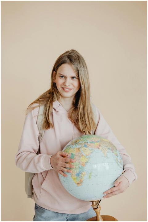 Teen girl in pink hoodie holding a globe, symboliz