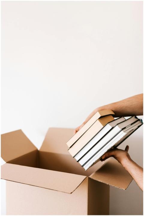Person organizing and packing books into a cardboa