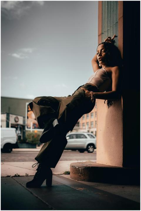 A fashionable woman leans casually against a colum