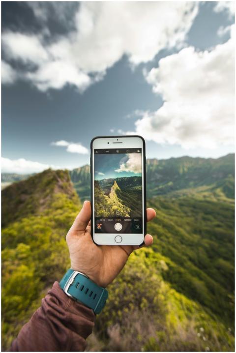 A person captures scenic mountains on a smartphone