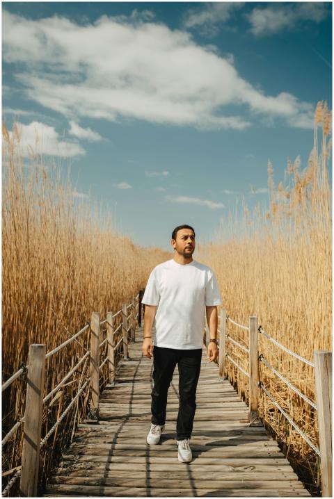 A man walks along a boardwalk through tall grass i