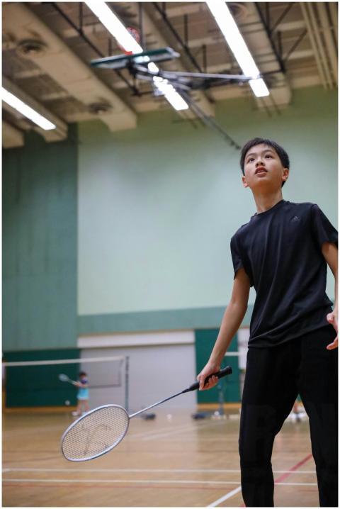 A young boy in sportswear intensely playing badmin