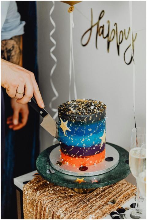 A colorful galaxy-themed cake being cut at a festi