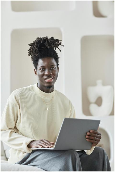 Smiling man with afro hair working on a laptop in