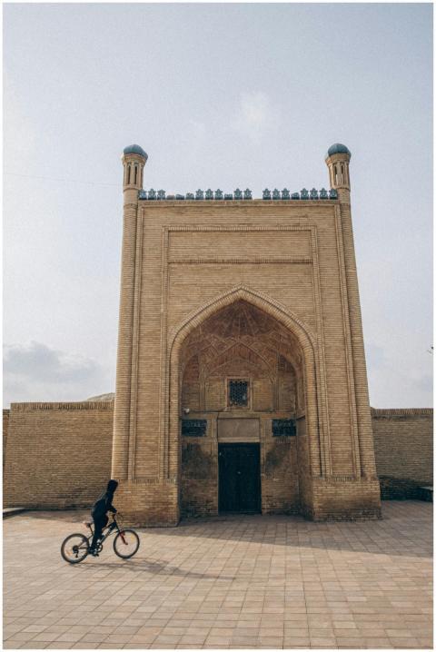 A lone cyclist rides past a historic brick structu