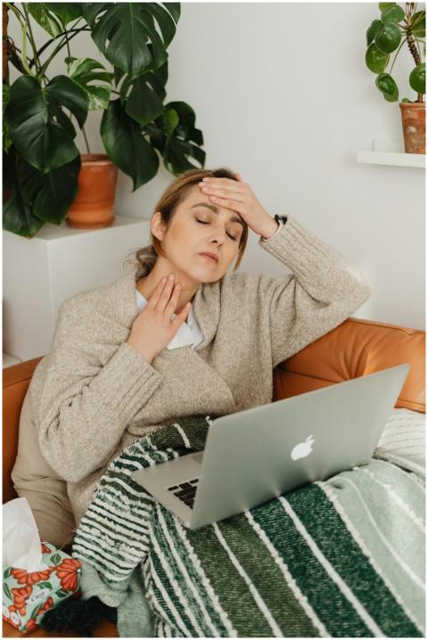 Woman with fever using a laptop while wrapped in a