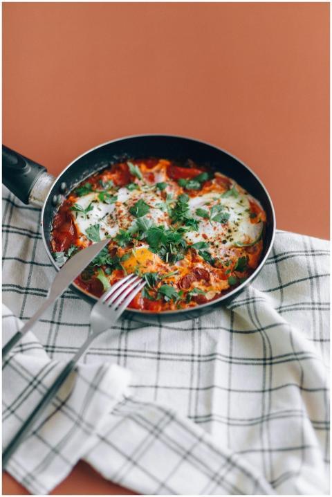 Fresh shakshuka in a skillet with herbs on a table