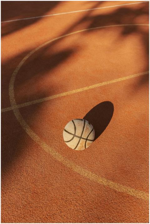 A basketball rests on an outdoor court with distin