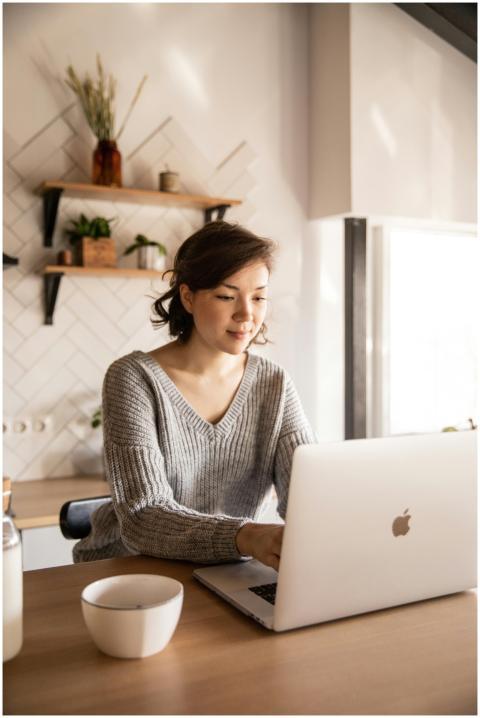 Young female in gray sweater sitting at wooden des