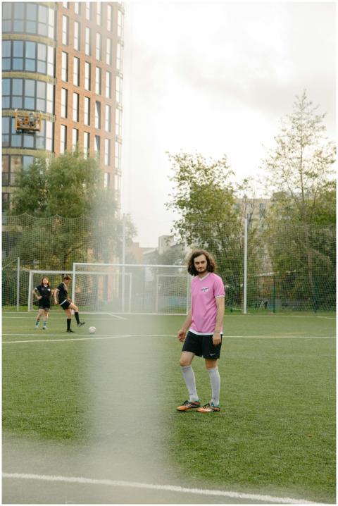 A young male soccer player stands on an outdoor fi