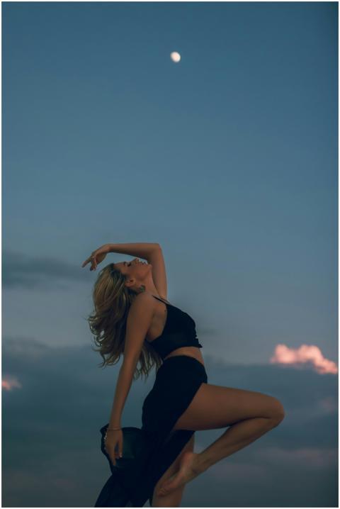 A woman gracefully dancing outdoors beneath the mo