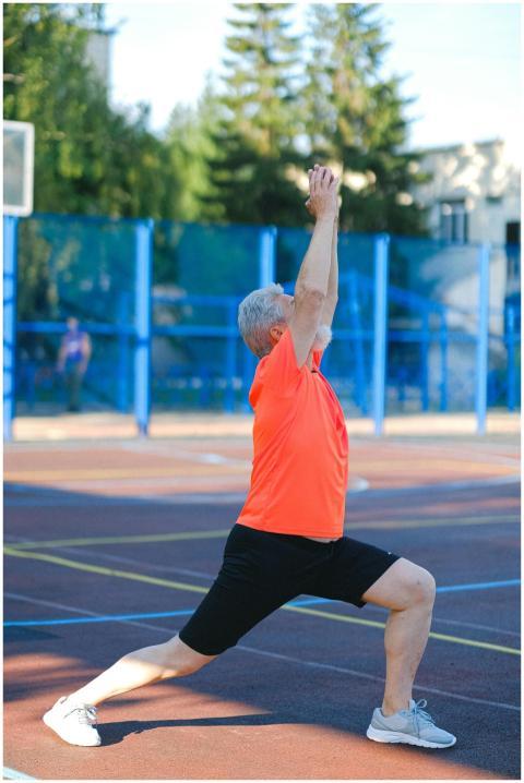 Elderly man in yoga warrior pose outdoors, focusin