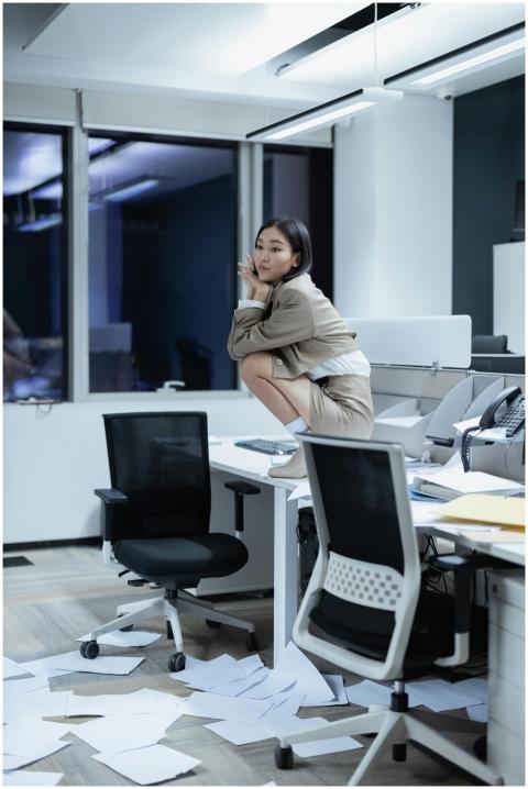 Woman in suit in modern office, papers scattered a