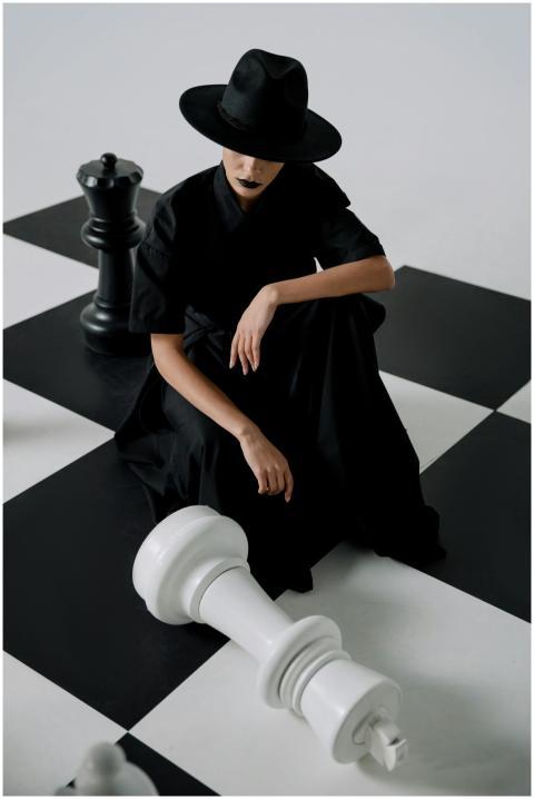 Stylish model in black attire on a chessboard, cre