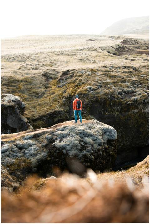 A lone hiker stands on rocky terrain in Vik í Mýrd