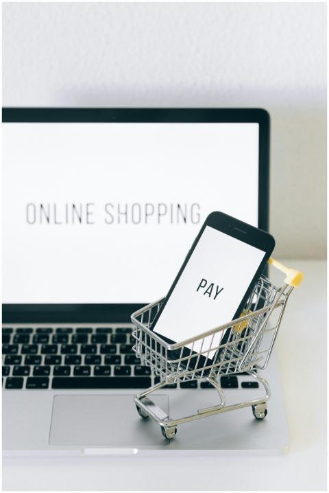 A smartphone in a miniature cart on a laptop symbo