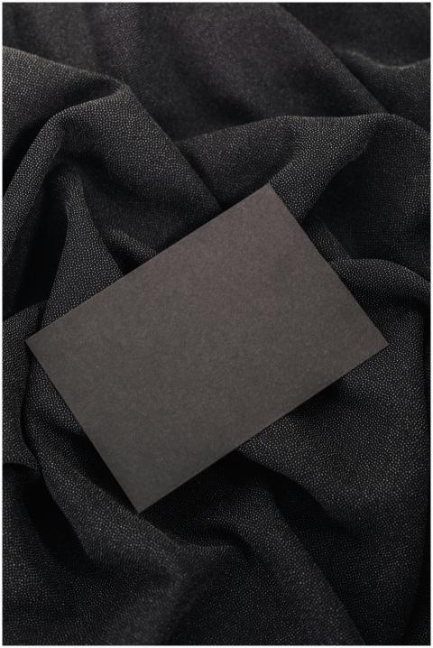 Black card on textured black fabric background, id