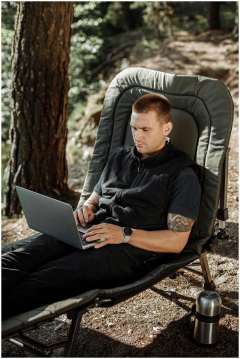 A man multitasks by working on his laptop in a ser