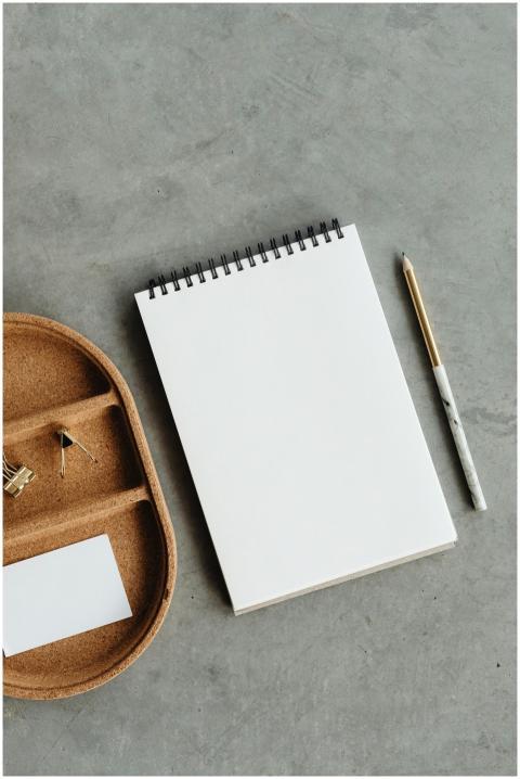 Flat lay of notepad, pencil, and binder clips on a