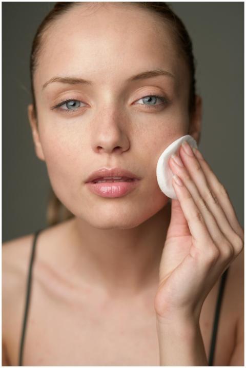 Young woman using a cotton pad for skincare, highl