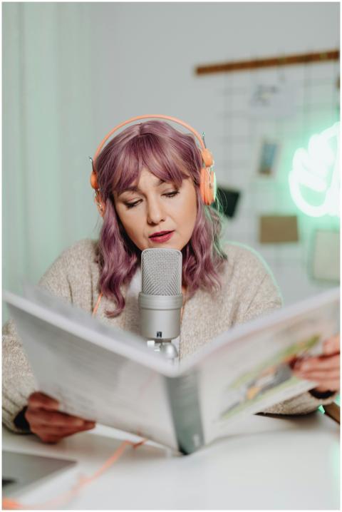 Woman podcasting indoors, reading from a book with