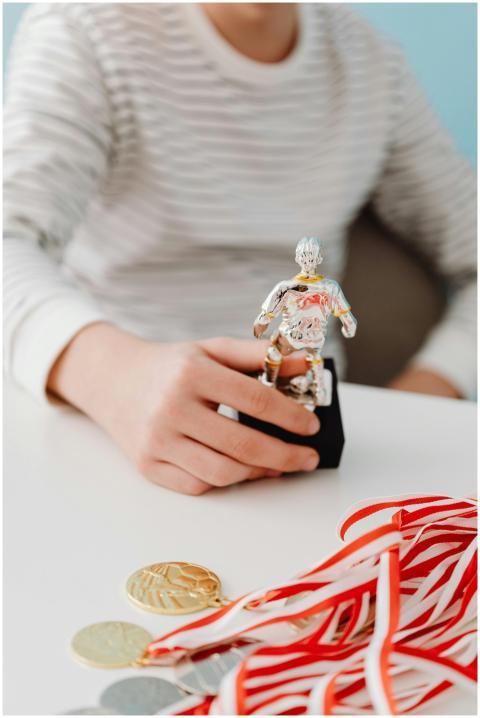 Teen in striped shirt holding soccer trophy with g