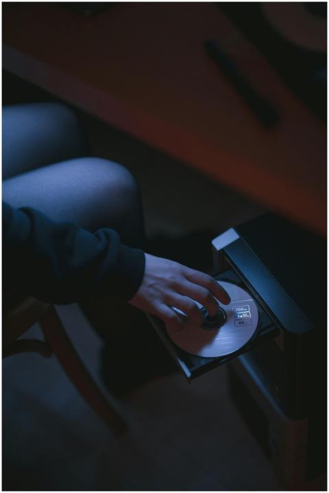 A person placing a compact disc into a computer di