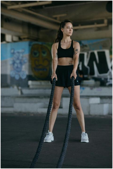 Young woman in activewear working out with battle