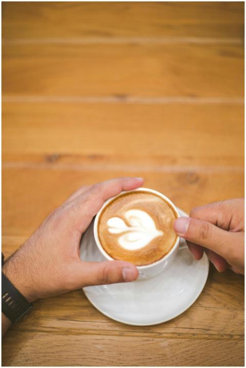 Top view of latte art with two hands holding the c