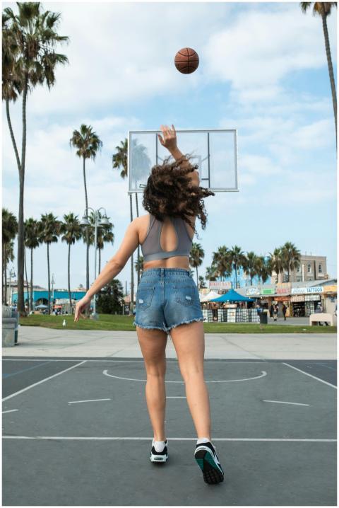 A woman in denim shorts plays basketball at an out